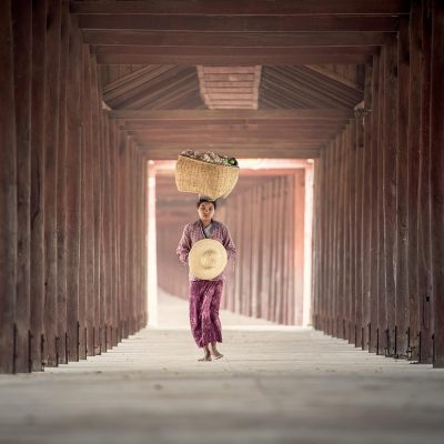 huay 编辑部主编沈砚舟的工作肖像，画面中他侧坐在堆满书籍的木质书架前，手里拿着一支钢笔在稿纸上标注，台灯暖光打在侧脸，背景是贴满便签的资料墙，呈现安静专注的编辑氛围